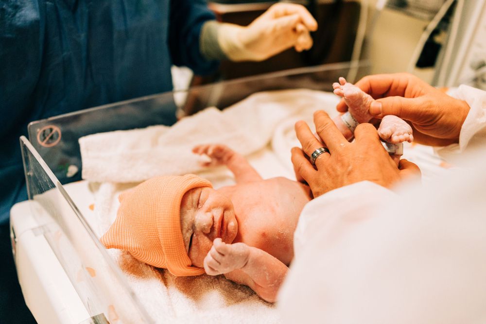 Newborn baby in baby warmer being comforted by his dad while still in the operating room, Santa Maria, CA