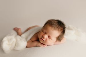 Professional studio newborn photography series with minimalist white backdrop.
