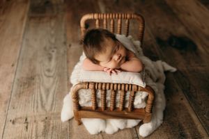 Rustic wooden backdrop with white knit blankets and soft neutral tones for newborn photography.