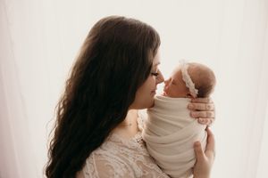 Intimate indoor portrait series with soft white backdrop and gentle embraces.