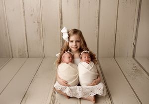 Studio photography session with siblings in white outfits against shiplap wall backdrop.
