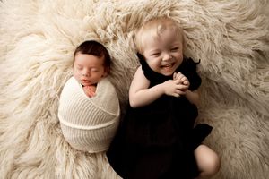 Sleeping baby on cream colored fluffy rug with black and white contrast.