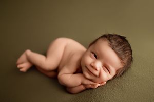 Minimalist newborn portrait series on olive green backdrop with natural lighting.