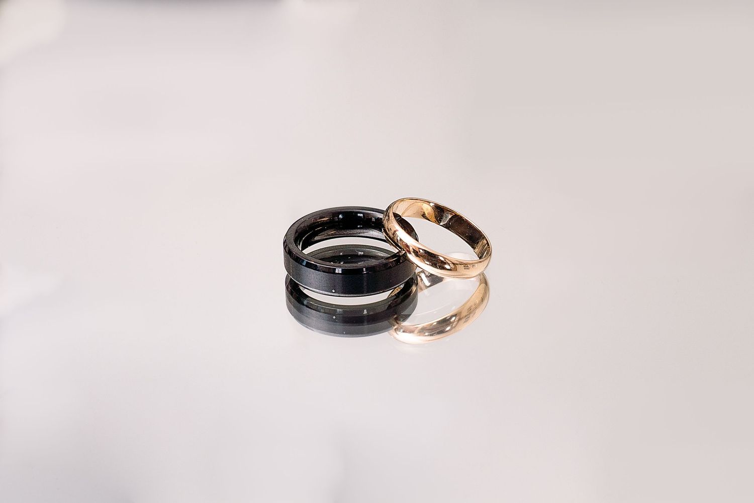 Three black and silver wedding bands arranged in a minimalist style on a light gray surface.