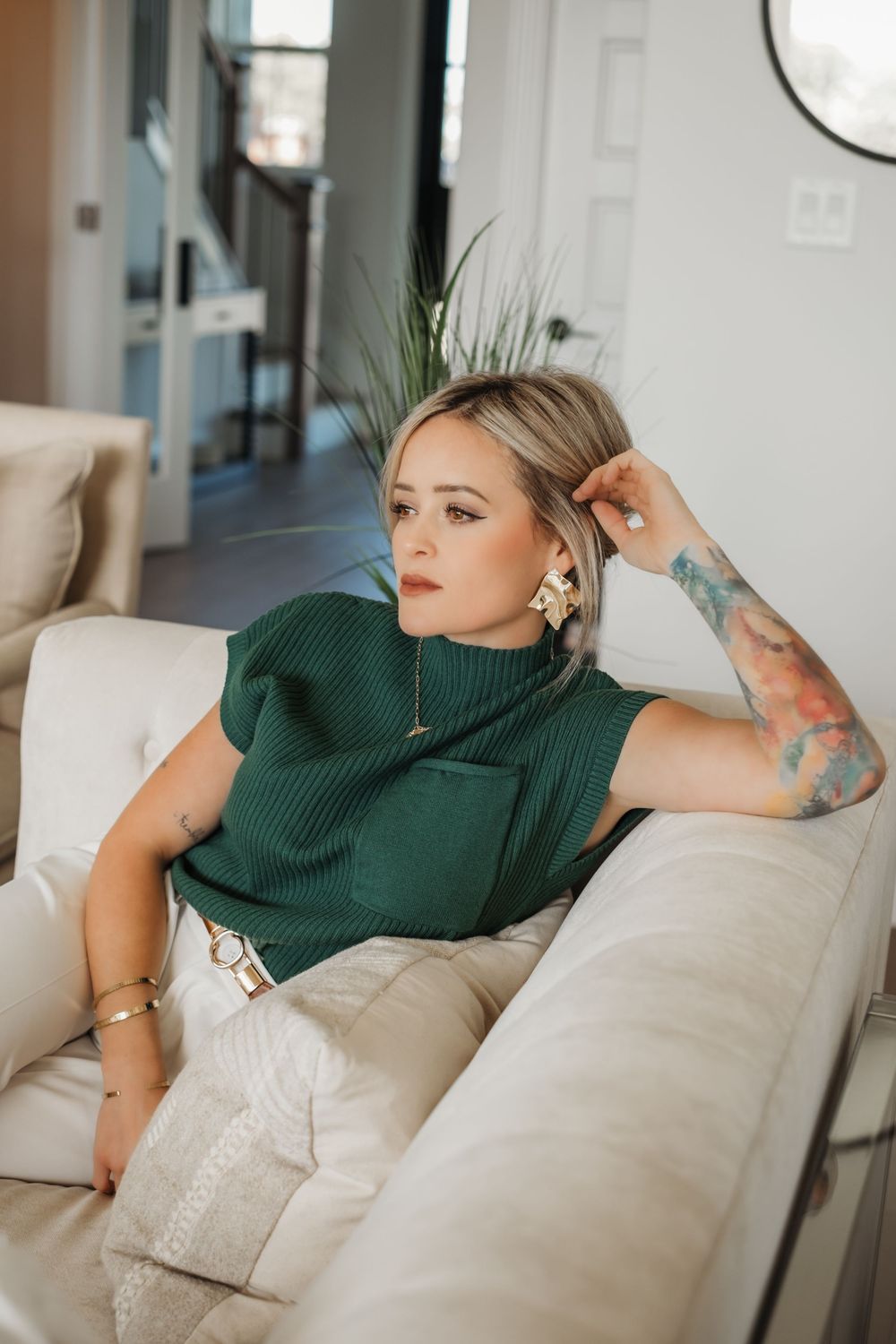 Person in green sweater lounges on cream colored couch in modern interior setting.