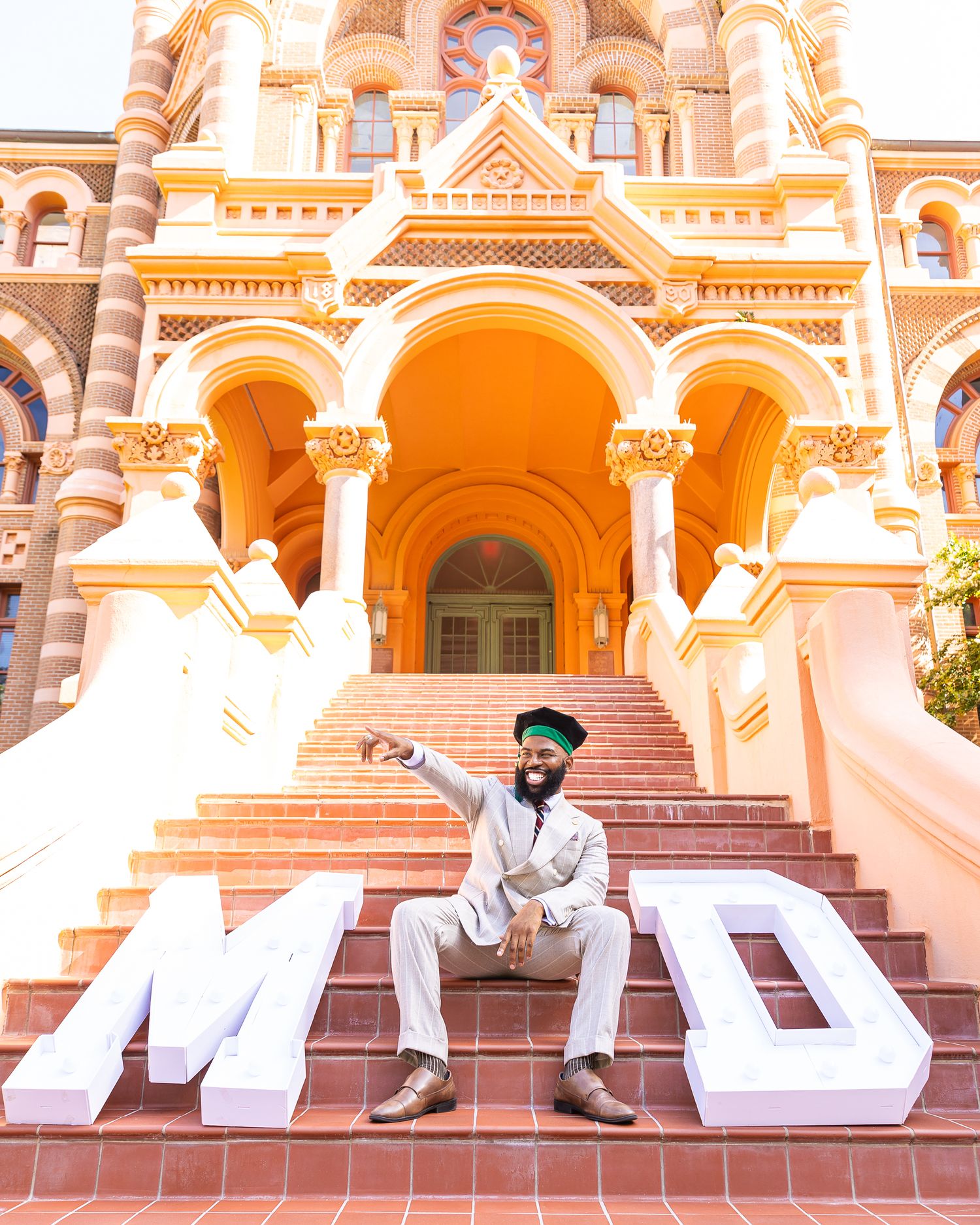 Large ornate building with peach-colored arches and decorative architecture featuring 'MD' block letters on its grand steps.