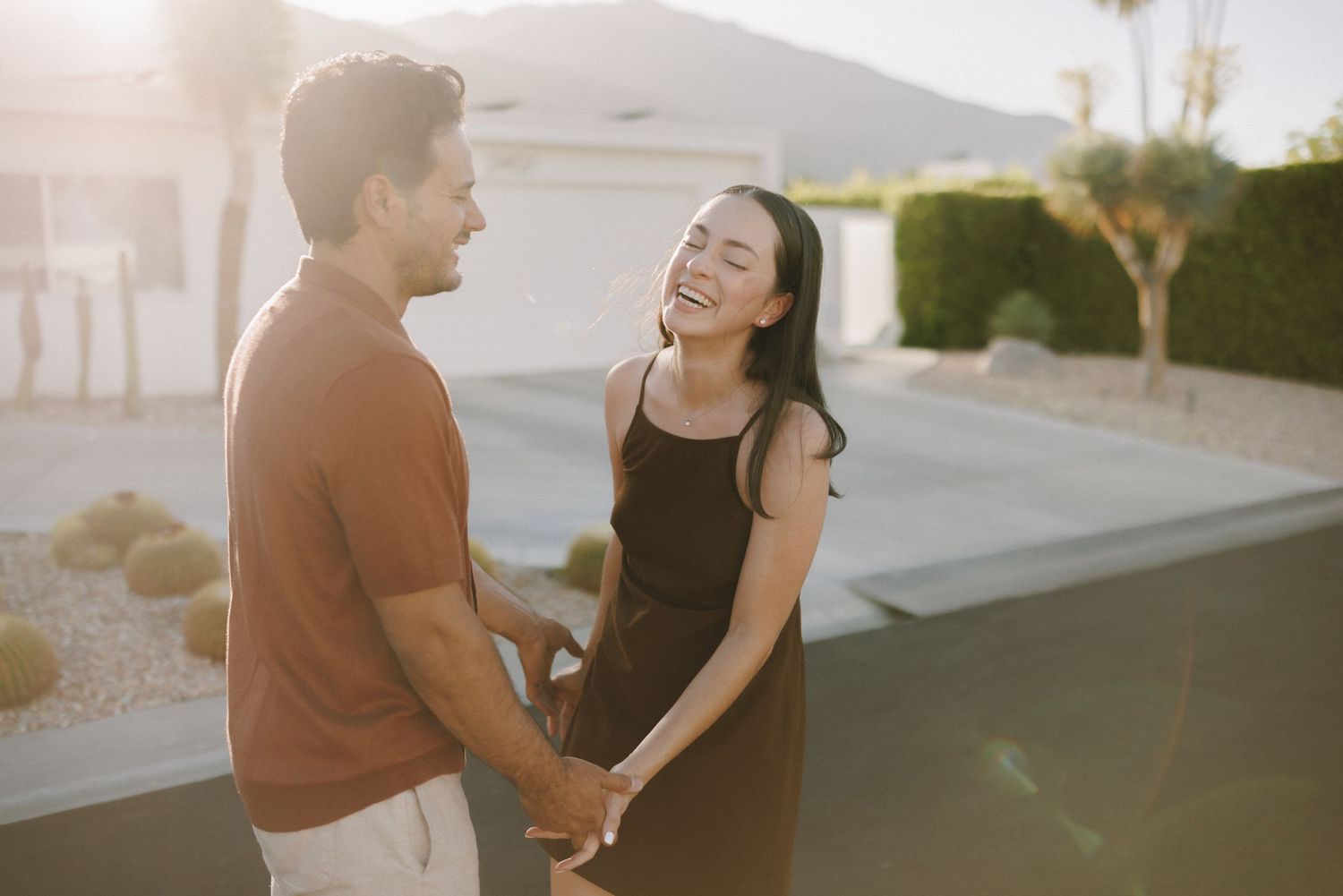 Couple shares intimate moment on sandy dunes during golden hour sunset.