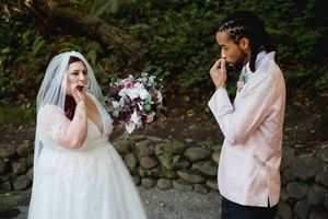 An emotional wedding moment between a bride in a white gown and a groom in a pink blazer sharing a tearful exchange.