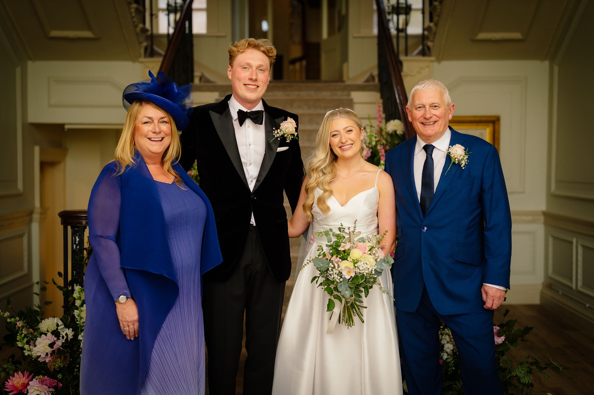 Formal wedding party portrait in an elegant indoor setting with classic decor.
