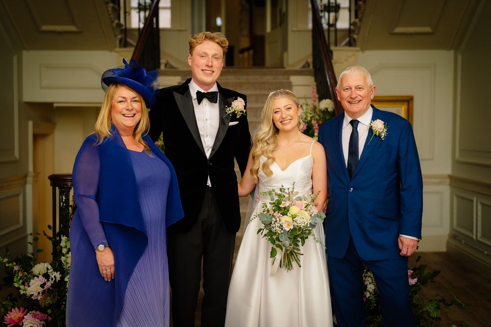 Formal wedding party portrait in an elegant indoor setting with classic decor.