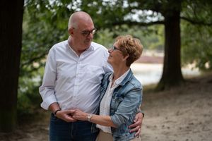 Romantic couple sharing tender moments in a park setting during a photo session.