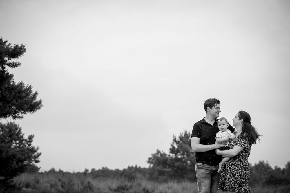 A romantic black and white portrait of a couple embracing in a natural outdoor setting.