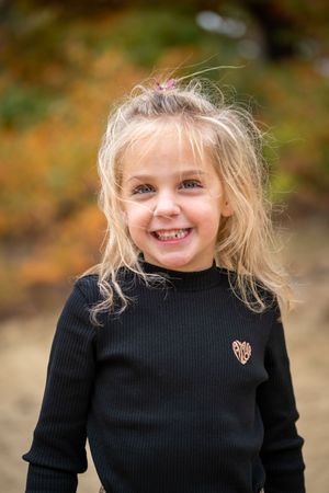 A series of four photos showing someone in a black sweater with blonde hair against an autumn background.