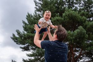 A playful moment captured against evergreen trees and cloudy sky.