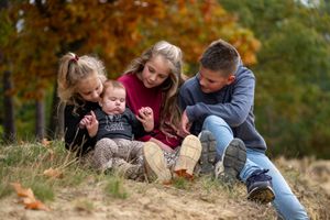 Family enjoying quality time together sitting on a grassy slope during fall season.