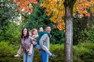 Family photoshoot in a park with vibrant autumn foliage.