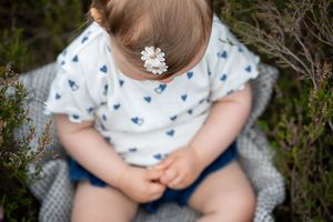 Close-up of a delicate white flower hair accessory on a blue and white patterned dress.