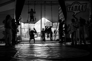 Black and white photo of circus performers silhouetted under a tent at Circus TADAA! show.