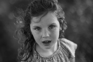 A black and white photo series shows close-up portraits of a child with curly hair and expressive features.
