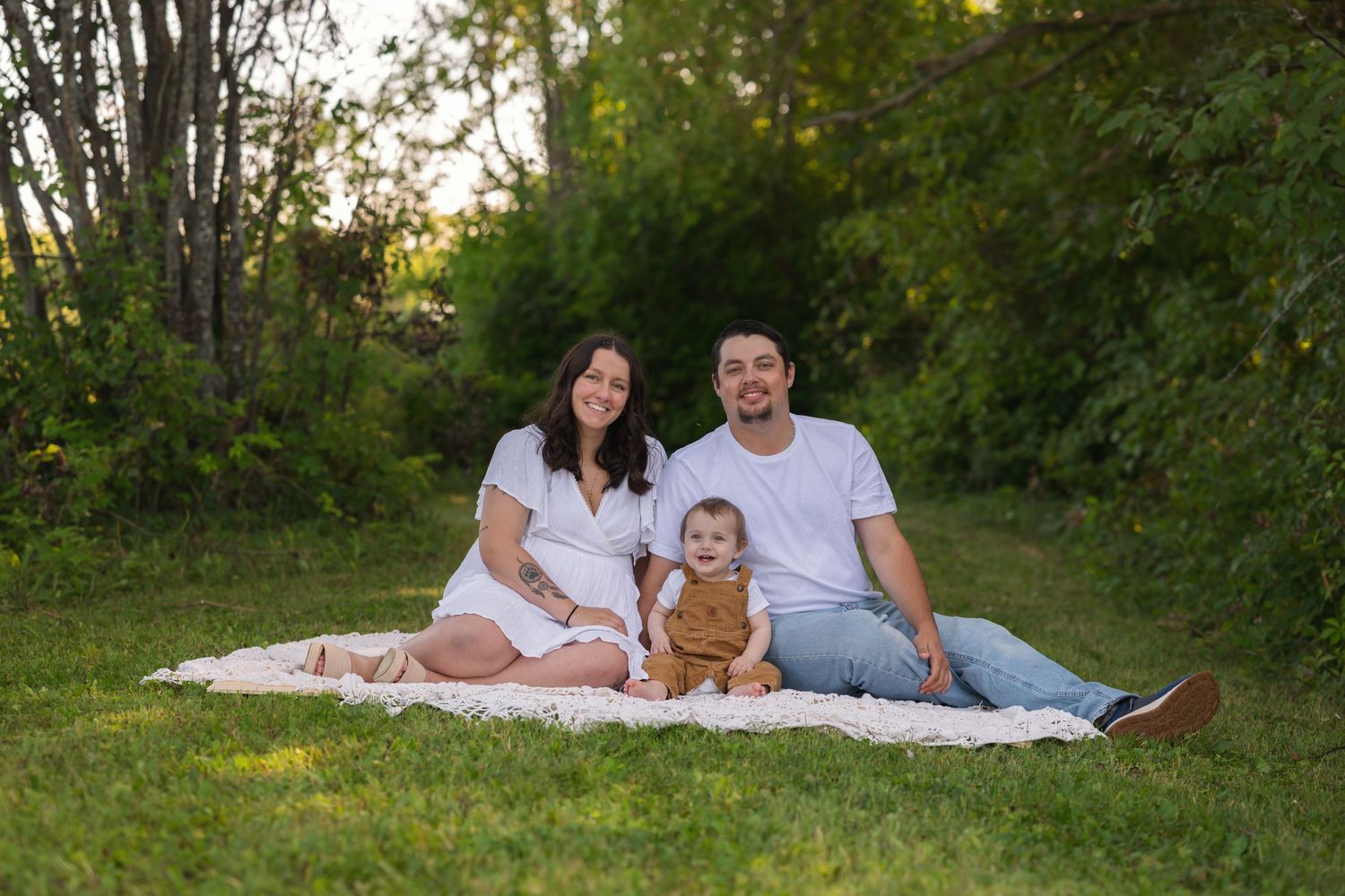 Family of 4 sitting on blanket in fall foliage