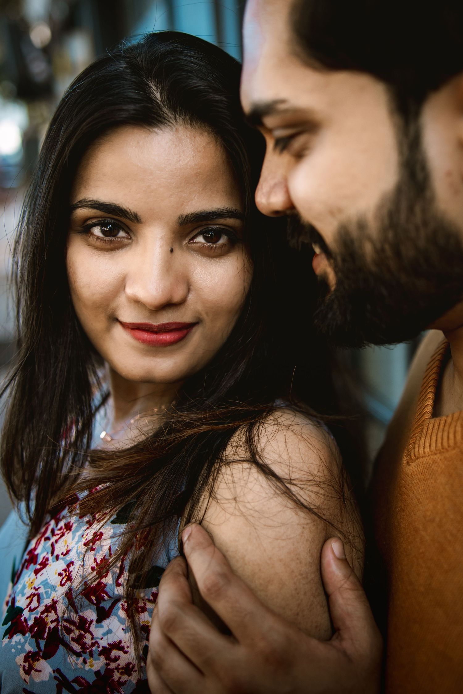 Romantic couple portrait with soft lighting and floral dress details.