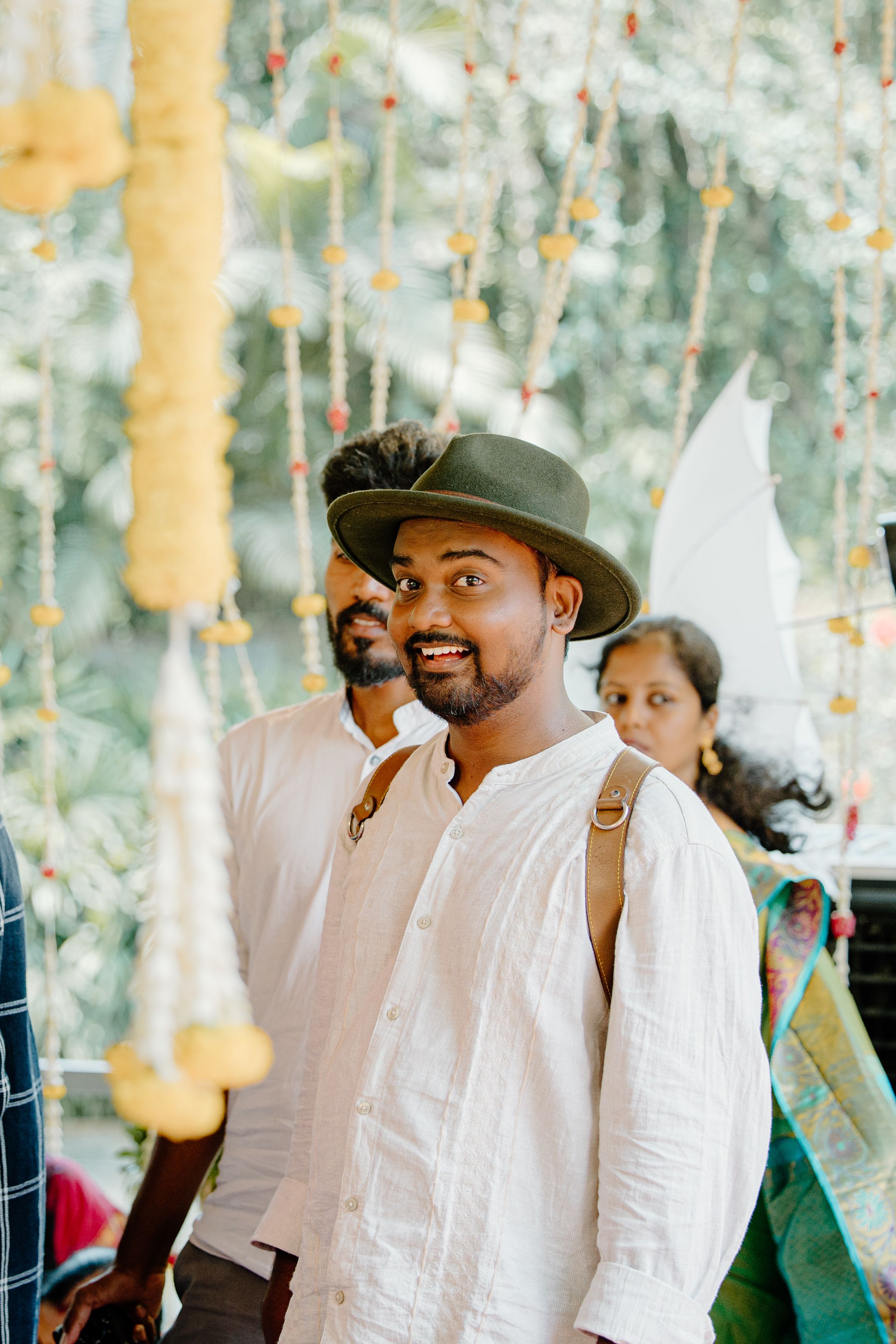 Group in white attire gathered outdoors with hanging lantern decorations.