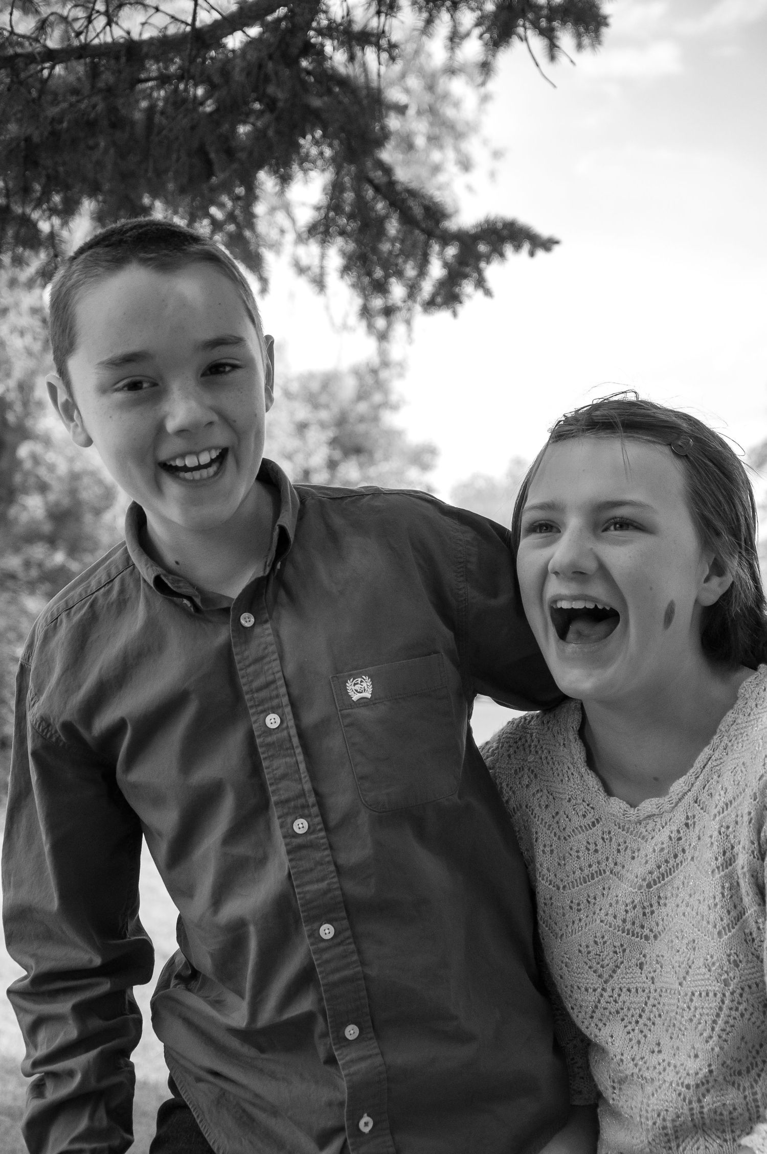 A brother and sister laugh together in this black and white photo
