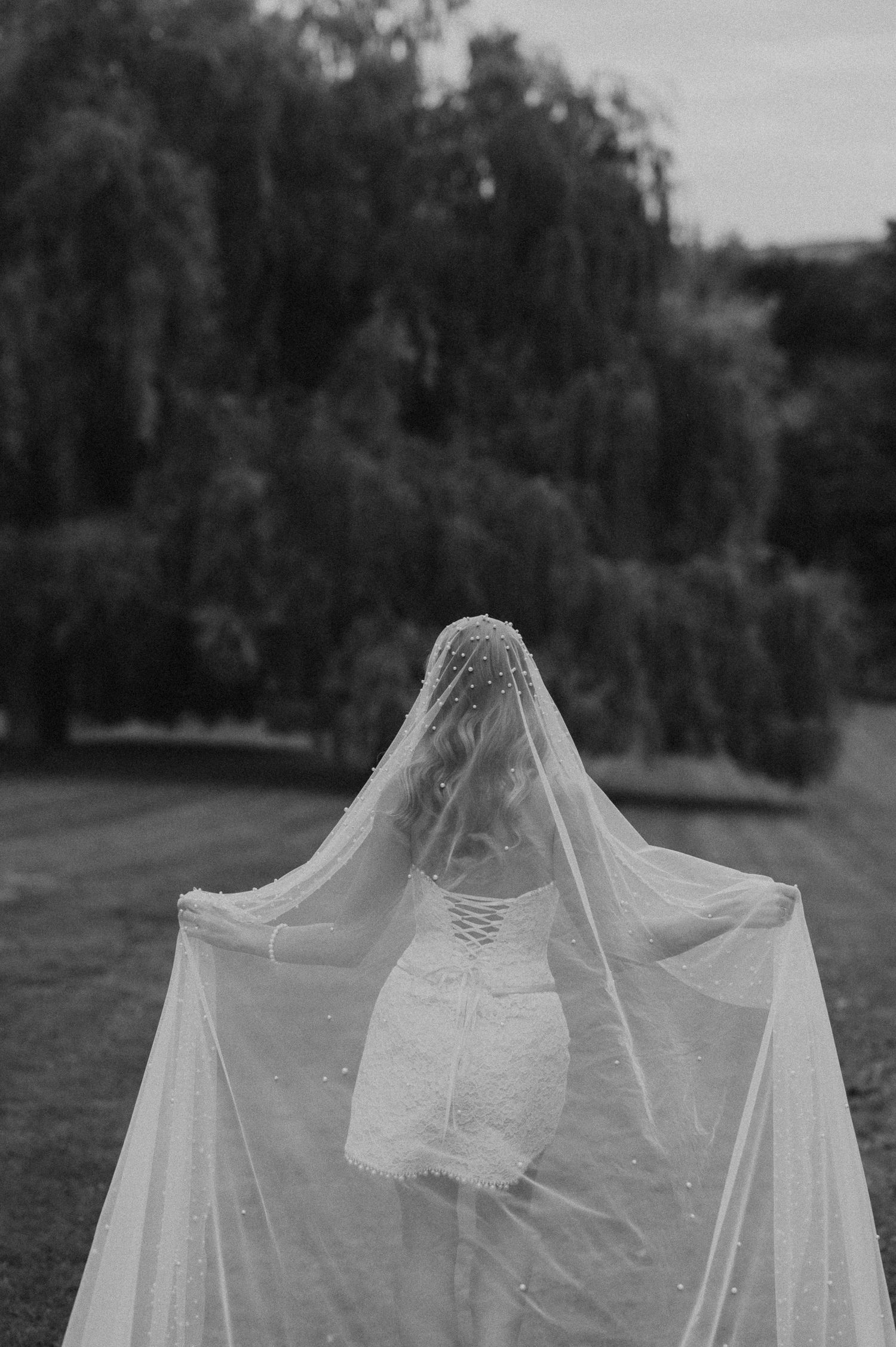 A black and white photo series of a bride in a flowing veil and wedding dress standing outdoors.