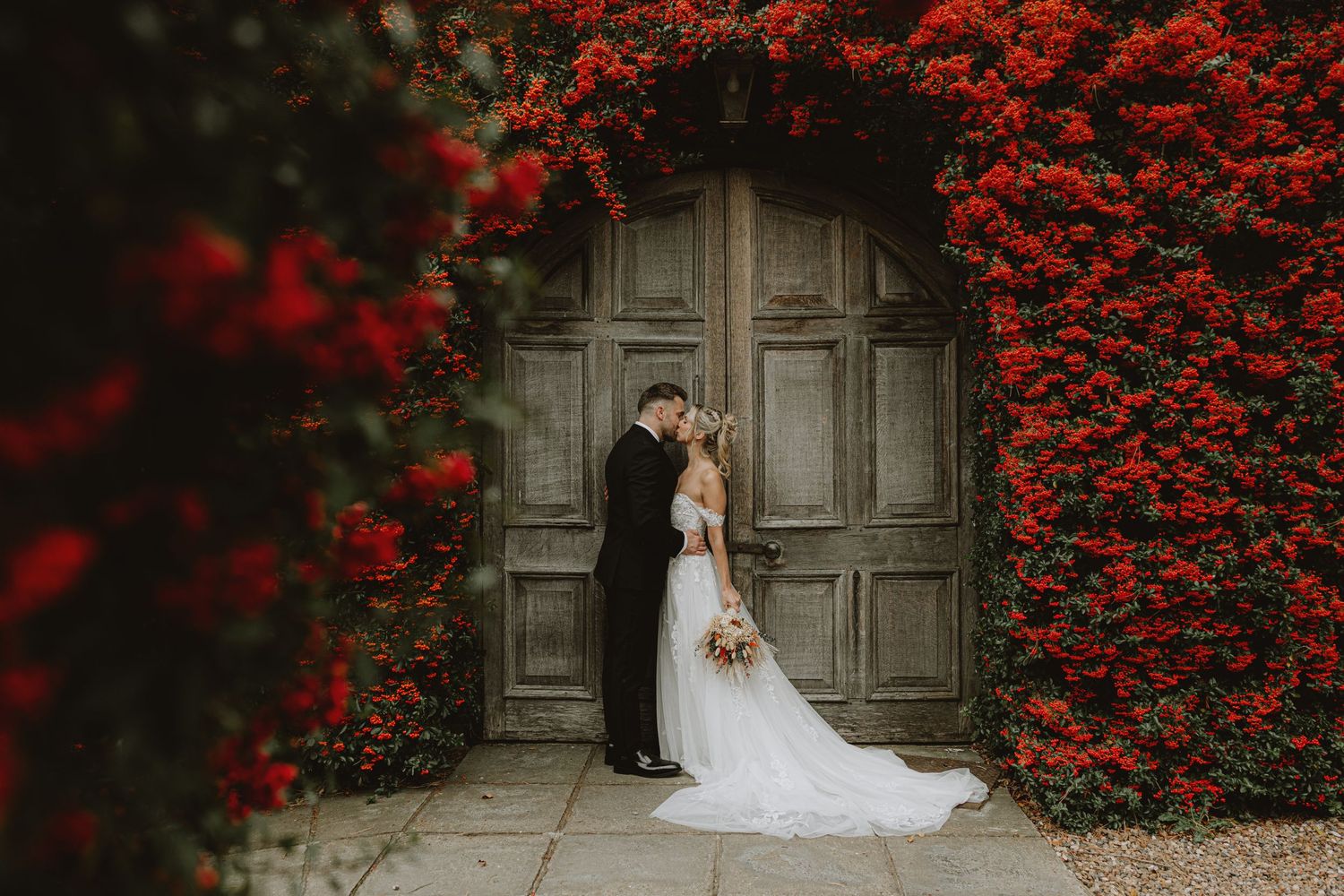 Stone wall backdrop with vibrant red bougainvillea flowers creating a romantic setting.