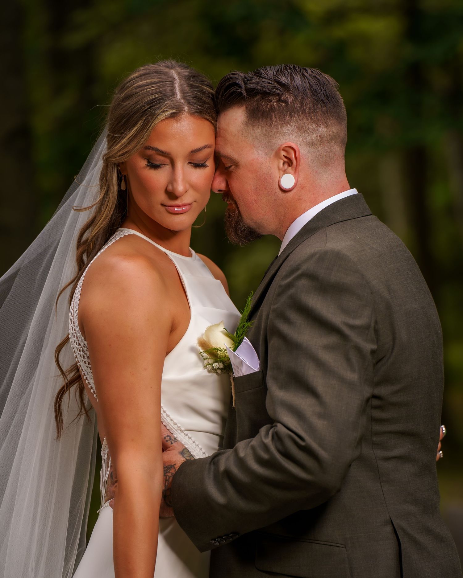 A romantic evening photo of a couple by a white fence with a flowing wedding dress.