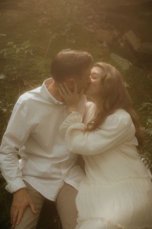 A dreamy sepia-toned portrait of a couple in white clothing sharing an intimate moment.