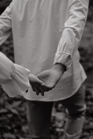 Black and white close-up of hands in white clothing against a dark background.