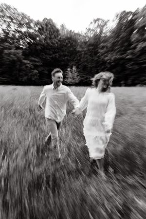 Couple running playfully through a grassy field in black and white motion blur sequence.