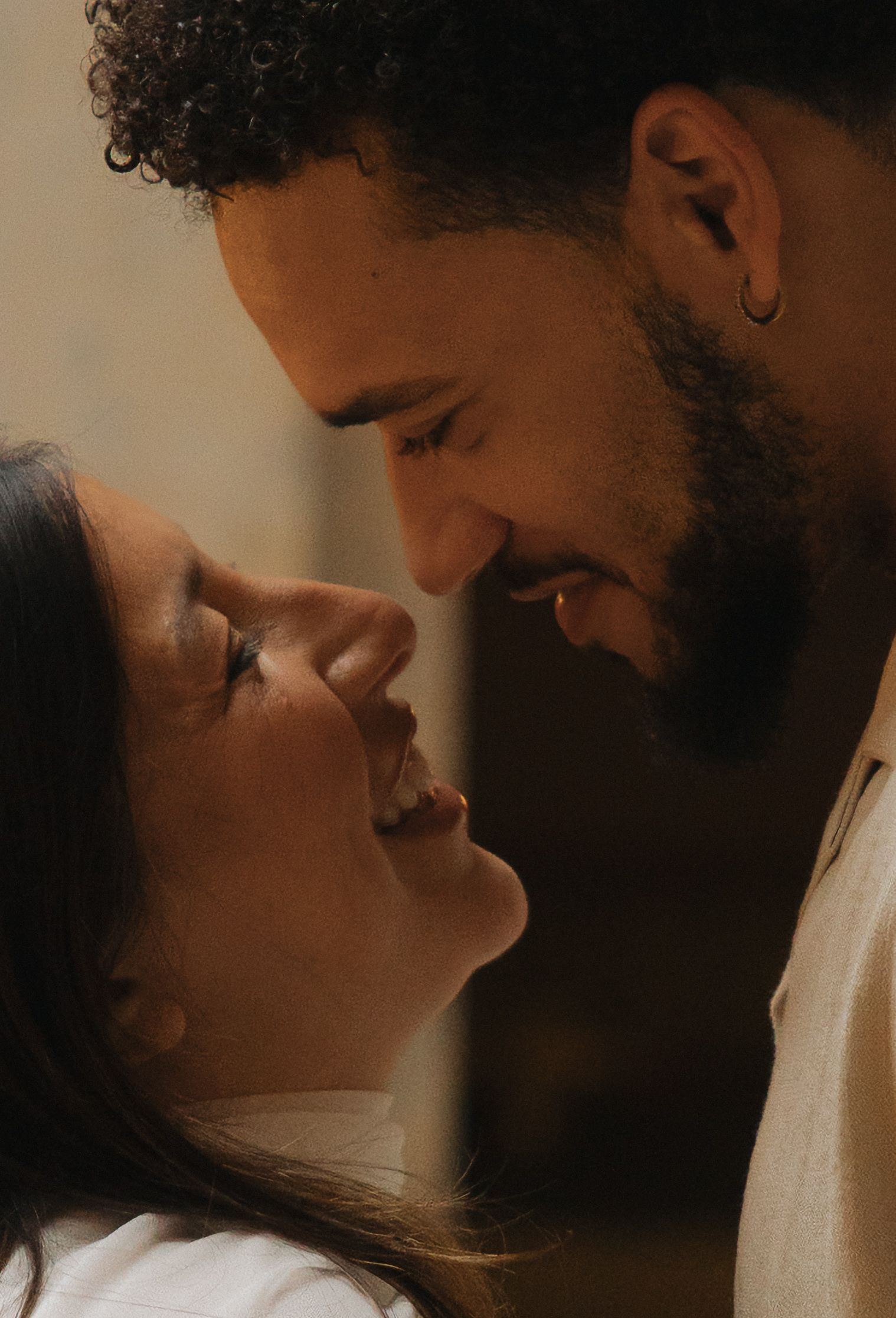 A romantic couple smiling and gazing at each other closely, sharing an intimate moment together.