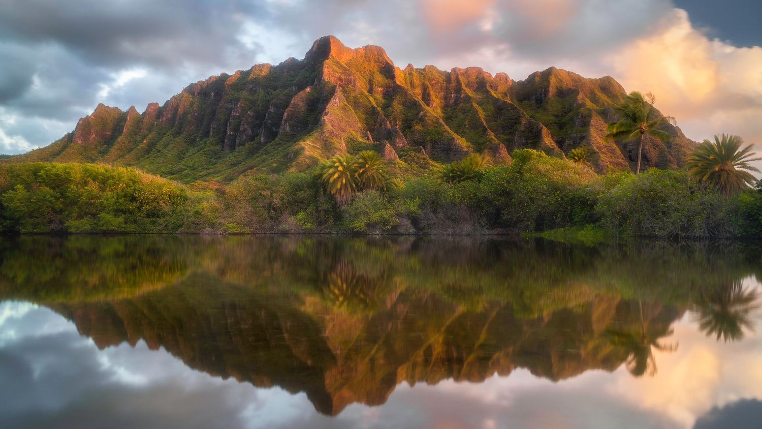 Dramatic mountain landscape reflected in still water during golden hour in Hawaii.