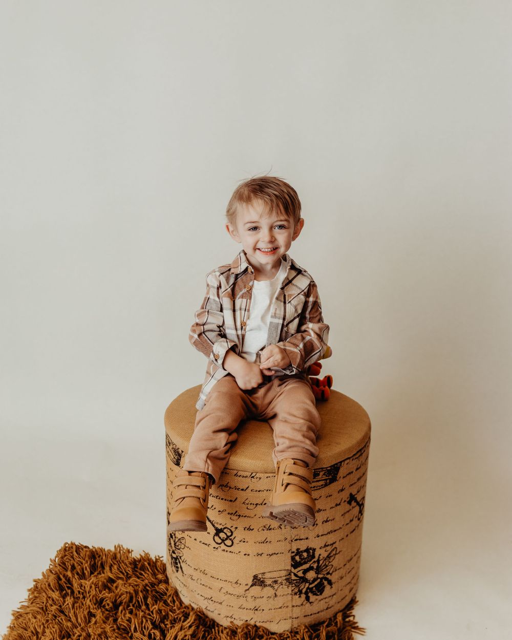 Lifestyle portrait on decorative cylindrical stool against neutral beige background.