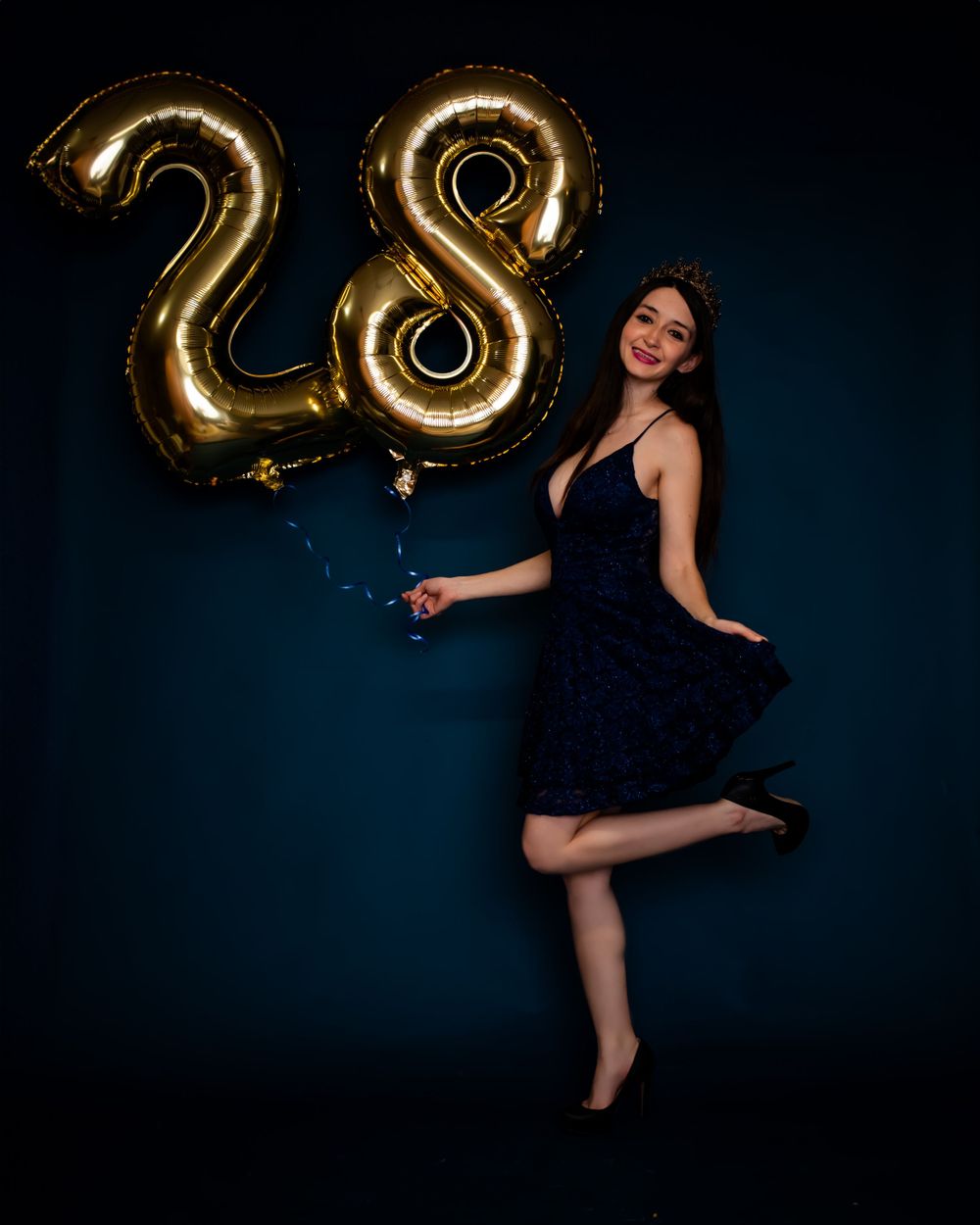 Birthday celebration with gold foil number 28 balloons against dark background.