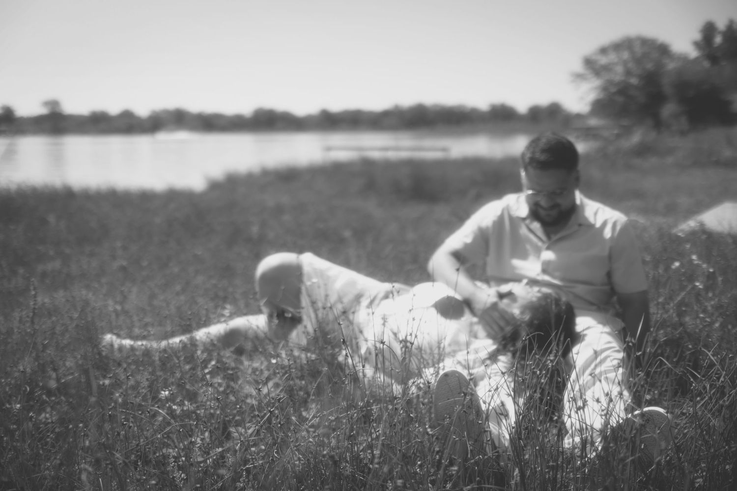 A person and dog relax together in a sunny meadow filled with wildflowers on a summer afternoon.
