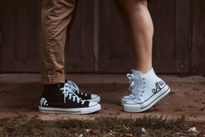 Close-up of two pairs of feet wearing casual sneakers standing close together.