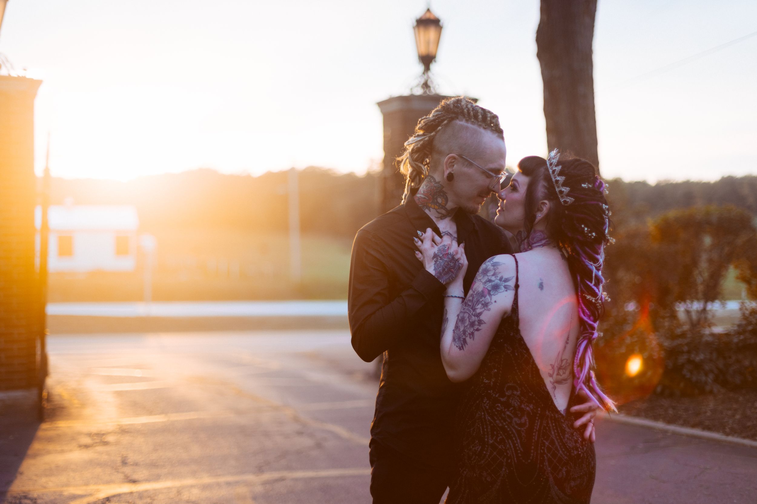 Couple shares intimate moment at sunset with golden light streaming behind them.