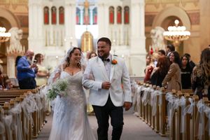 A joyful newlywed couple walks down the church aisle together after their wedding ceremony.