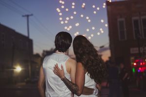 A romantic evening scene with glowing string lights illuminating a couple sharing an intimate moment at dusk.