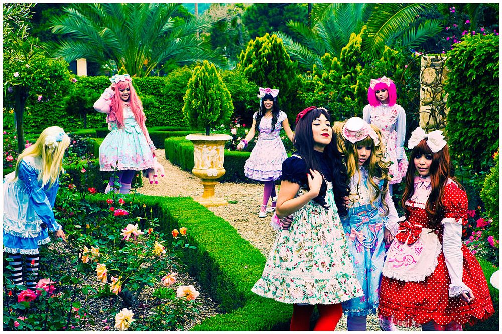 A group of people enjoying a garden party with colorful outfits and lush greenery in the background.