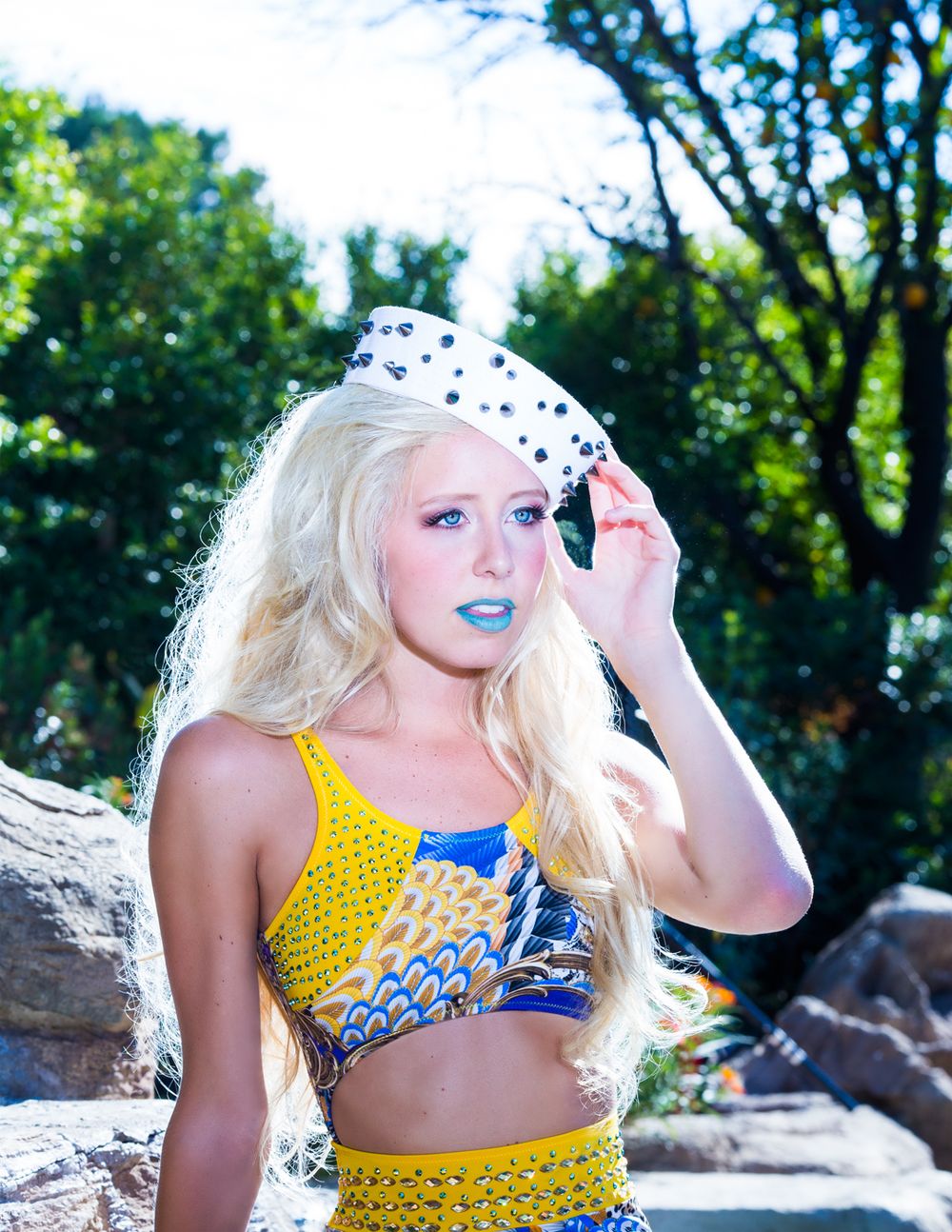 A series of fashion shots featuring yellow polka dot swimwear against a sunny outdoor backdrop with rocks and trees.