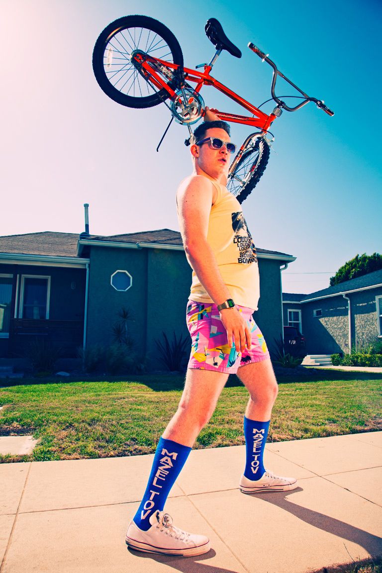 Sequence showing someone lifting a red bicycle overhead on a sunny day outside suburban homes.