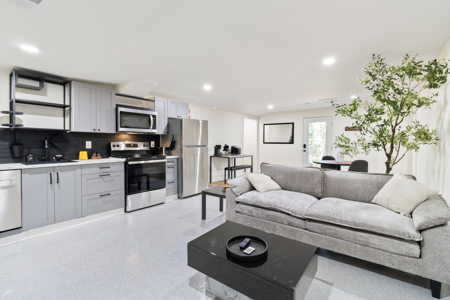 Open concept living space with washer-dryer alcove and modern white kitchen.