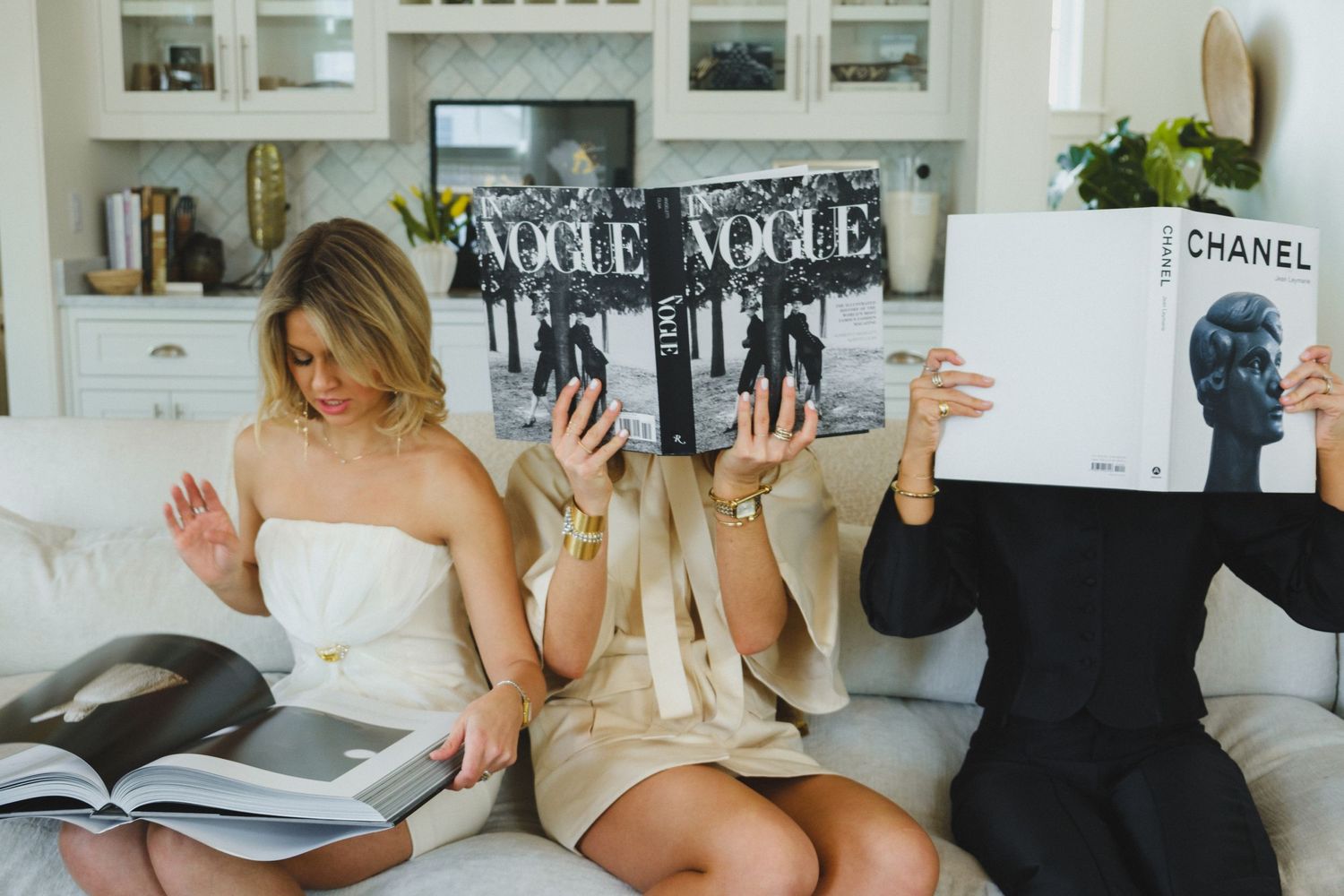 People reading and relaxing in a bright white modern room with books and photographs on display.