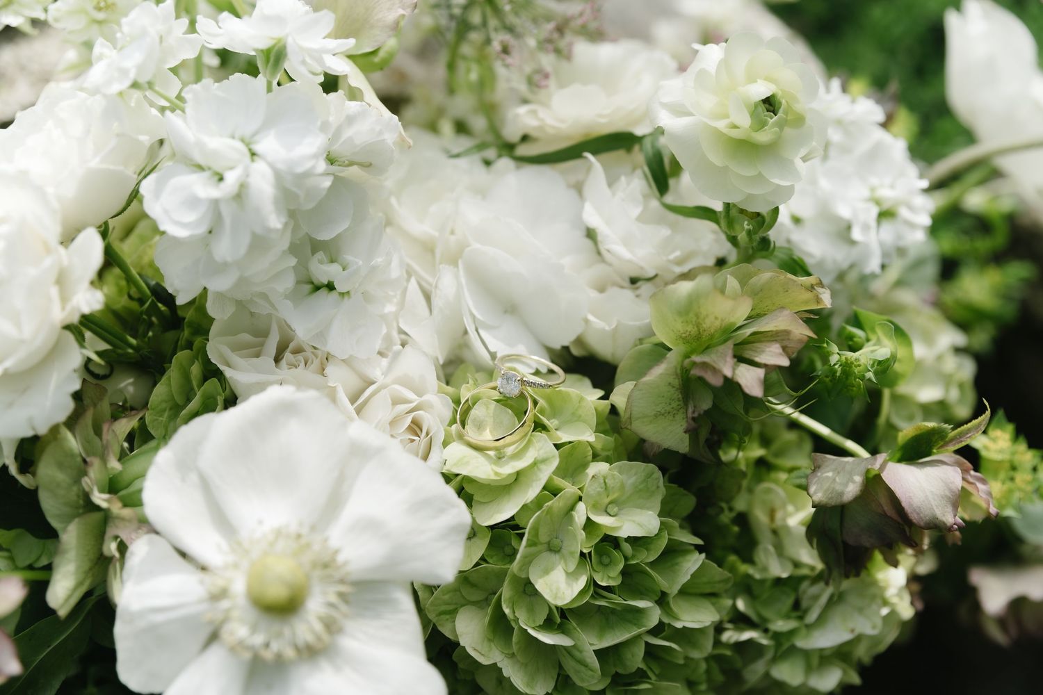 Close-up of elegant white and green floral arrangement featuring hydrangeas, peonies, and anemones.