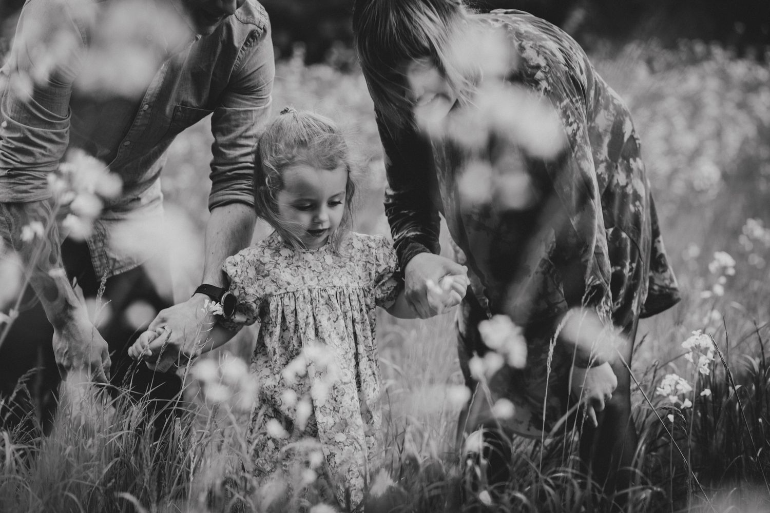Family walking through a sunny meadow of yellow wildflowers on a spring day.