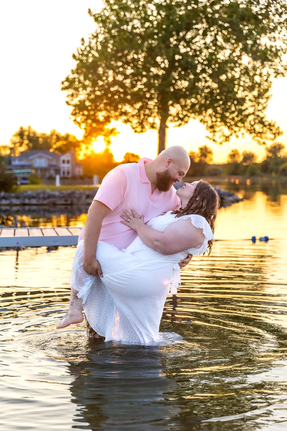 Romantic sunset photoshoot in water showing couple embracing and dipping in golden light during sunset.